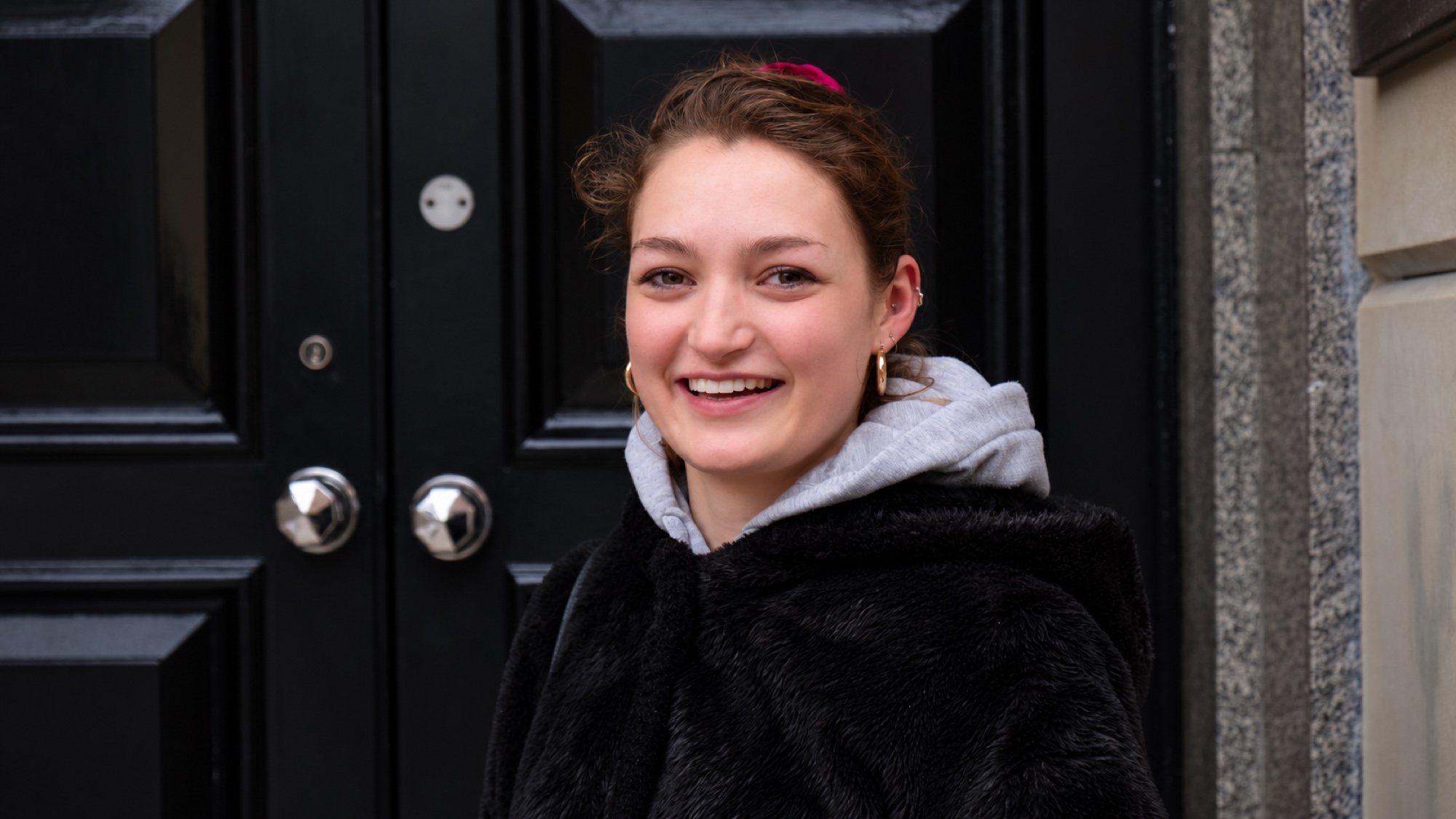 Preview photo of a smiling person outside a dark doorway